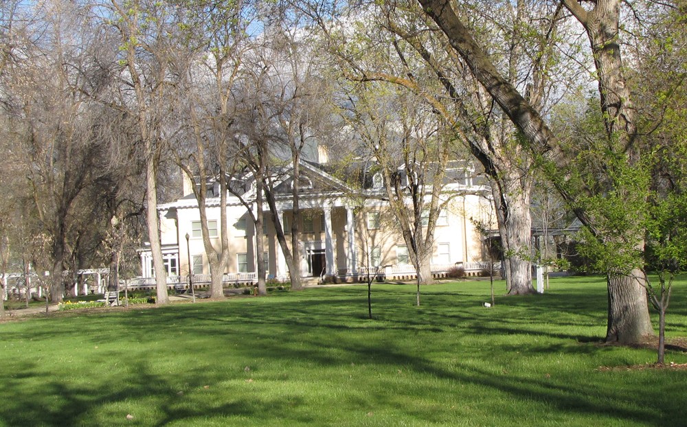 A large white house surrounded by trees and green grass.